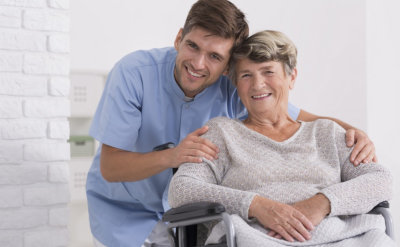 male nurse hugging his senior women patient sitting on a wheelchair 